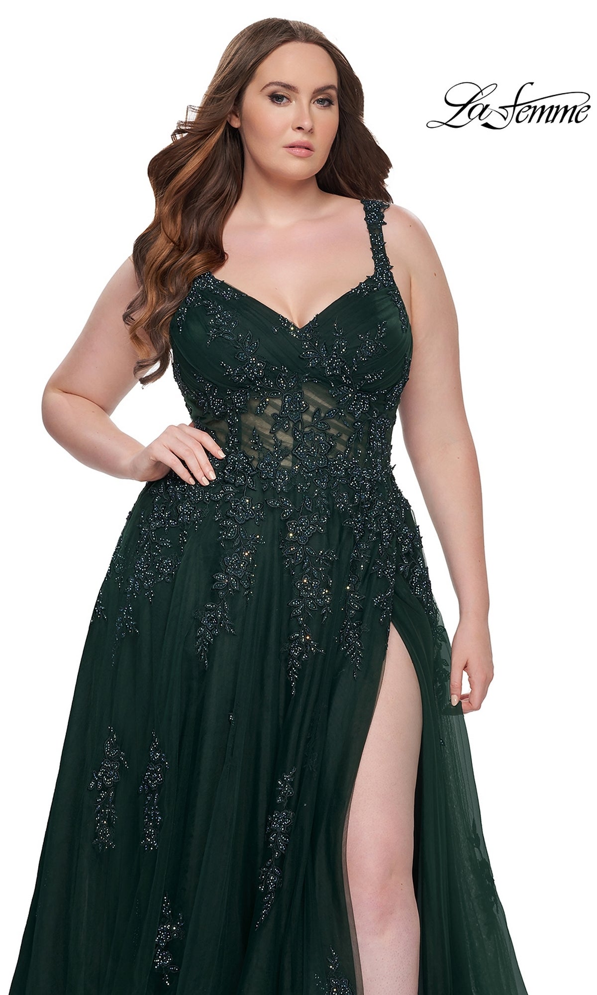A woman models the La Femme Long Prom Dress 31383, a dark green plus-size lace gown with embroidery, sheer bodice, and thigh-high slit, set against a white background.